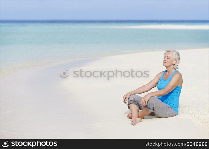 Senior Woman Meditating On Beautiful Beach