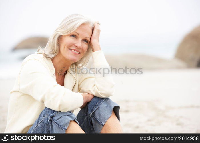 Senior Woman On Holiday Sitting On Winter Beach