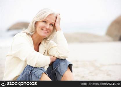 Senior Woman On Holiday Sitting On Winter Beach