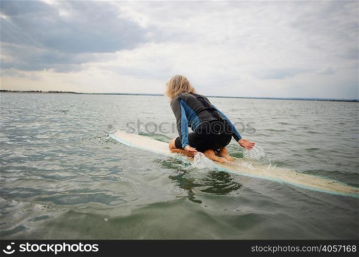 Senior woman on surfboard in sea, paddleboarding