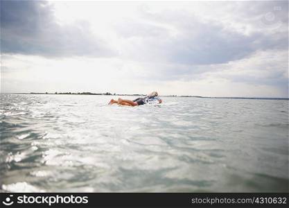 Senior woman on surfboard in sea, paddleboarding