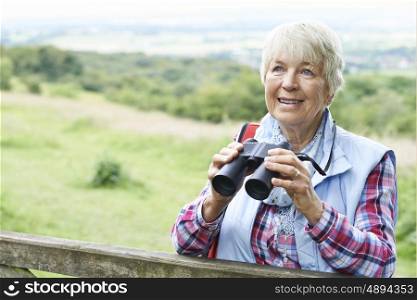 Senior Woman On Walk With Binoculars In Countryside