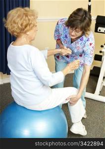 Senior woman on yoga ball, working with a physical therapist.