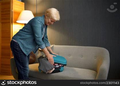 Senior woman packing luggage for new journey. Ready for travelling. Happy vacation on retirement. Senior woman packing luggage for new journey