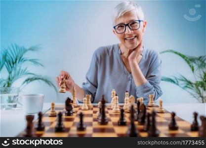 Senior woman playing chess. Cognitive rehabilitation activity.. Cognitive Rehabilitation Activity. Senior Woman Playing Chess.