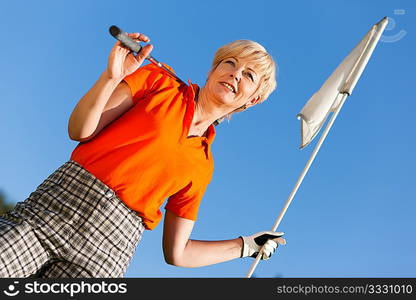 Senior woman playing golf holding the flag in her hand