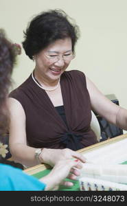 Senior woman playing mahjong and smiling