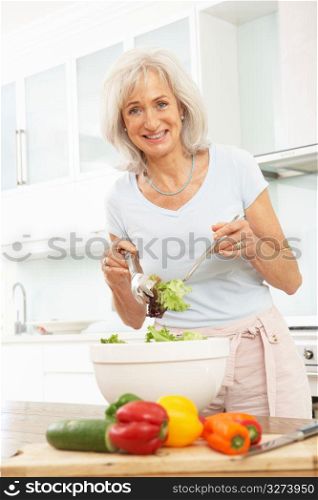 Senior Woman Preparing Salad In Modern Kitchen
