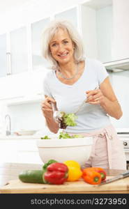 Senior Woman Preparing Salad In Modern Kitchen