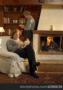 Senior woman reading book by fire