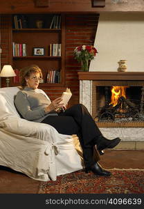 Senior woman reading book by fire