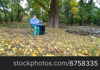 Senior Woman Reading Book in Autumn Park. lockdown, Wide Angle
