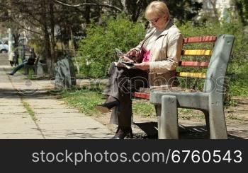 Senior Woman Reading Fashion Magazine In The City Park