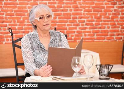 Senior woman reading menu at the restaurant
