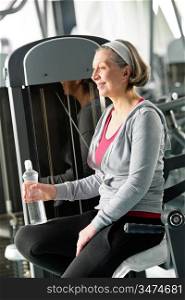 Senior woman relax at gym sitting by fitness machine