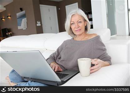 Senior woman relaxing at home in front of laptop computer
