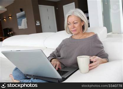 Senior woman relaxing at home in front of laptop computer