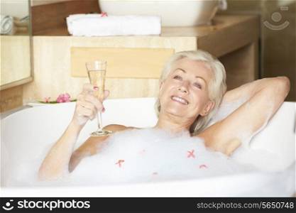 Senior Woman Relaxing In Bath Drinking Champagne