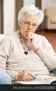 Senior Woman Relaxing In Chair At Home Completing Crossword