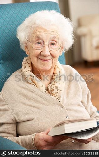 Senior Woman Relaxing In Chair At Home Reading Book