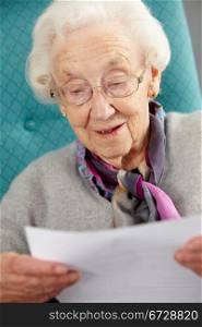 Senior Woman Relaxing In Chair Reading Letter