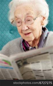Senior Woman Relaxing In Chair Reading Newspaper