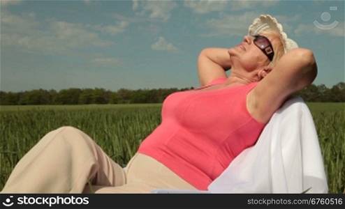 Senior woman relaxing on a green meadow
