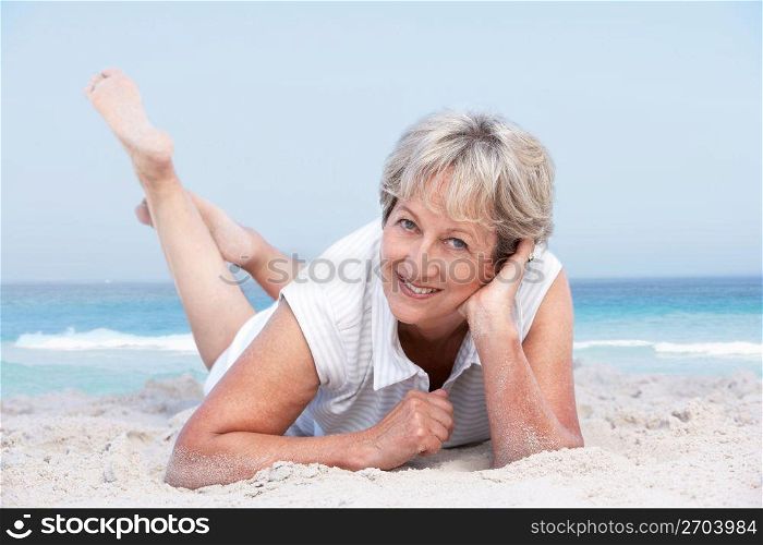 Senior Woman Relaxing On Sandy Beach