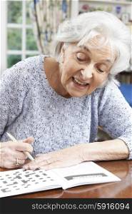 Senior Woman Relaxing With Crossword Puzzle At Home