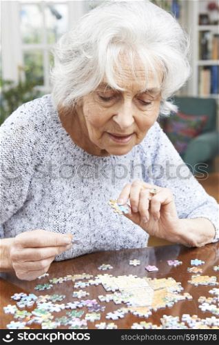 Senior Woman Relaxing With Jigsaw Puzzle At Home