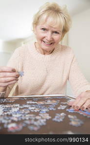 Senior Woman Relaxing With Jigsaw Puzzle At Home