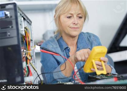 senior woman repairing computer in her office