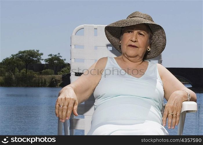 Senior woman resting on a chair at the lakeside