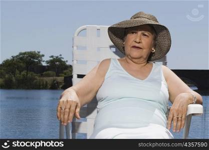 Senior woman resting on a chair at the lakeside