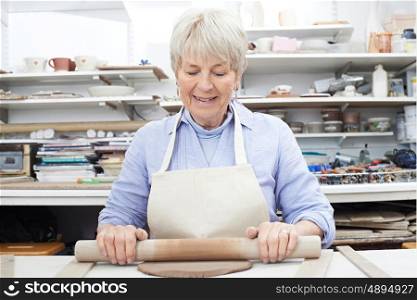Senior Woman Rolling Out Clay In Pottery Studio