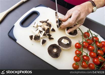 Senior woman&rsquo;s hand chopping mushrooms on cutting board
