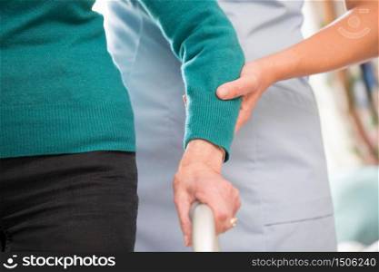 Senior Woman&rsquo;s Hands On Walking Frame With Care Worker In Background