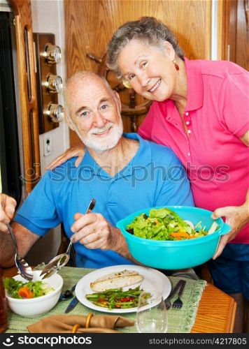 Senior woman serves a healthy dinner to her husband in their modern motor home.