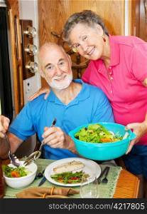 Senior woman serves a healthy dinner to her husband in their modern motor home.