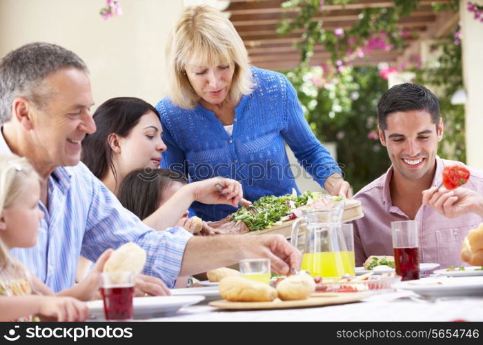 Senior Woman Serving At Multi Generation Family Meal