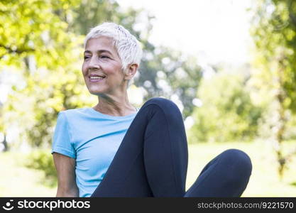 Senior woman sitting and resing after workout in park