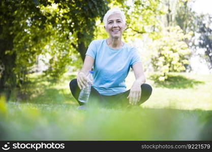 Senior woman sitting and resting after workout in park