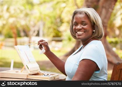 Senior Woman Sitting At Outdoor Table Painting Landscape