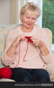 Senior Woman Sitting In Chair Knitting