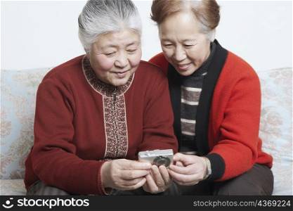 Senior woman sitting with a mature woman holding a digital camera