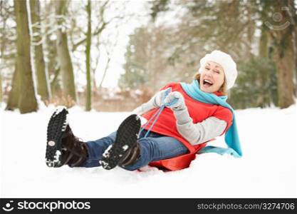 Senior Woman Sledging Through Snowy Woodland