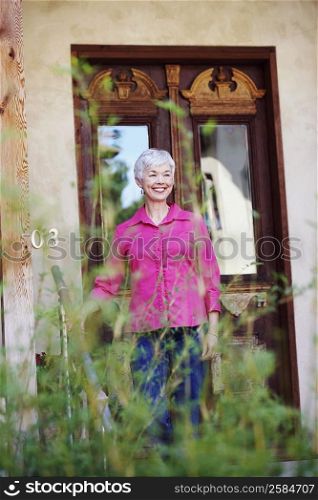 Senior woman standing in front of a closed door and smiling