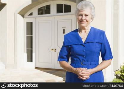 Senior woman standing outside her home