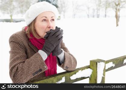 Senior Woman Standing Outside In Snowy Landscape Warming Hands