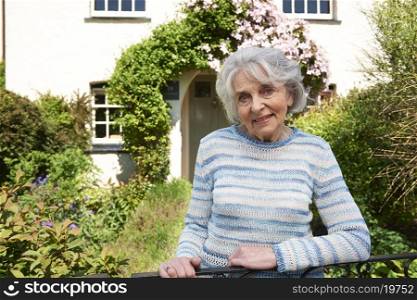 Senior Woman Standing Outside Pretty Cottage